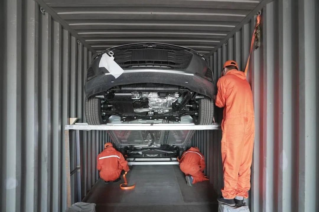 Workers securing a vehicle inside a container